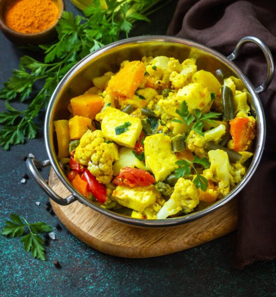 Sabji, Stewed pumpkin with soft cheese and vegetables on a dark stone table. Traditional Indian food. Copy space.