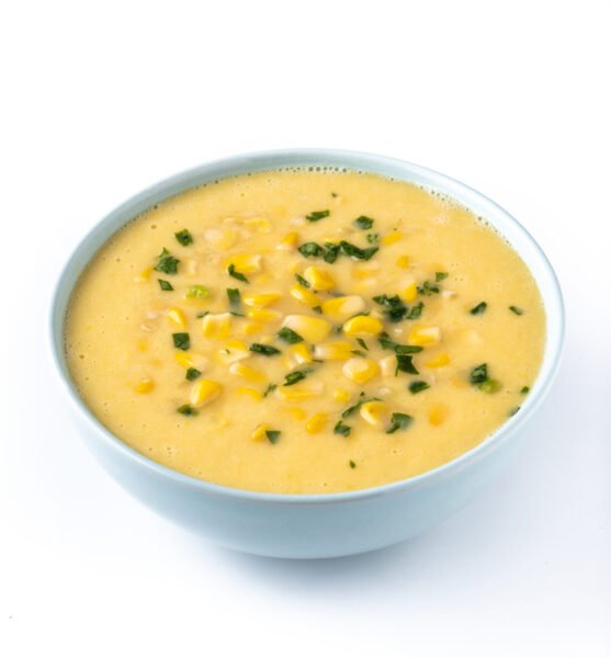 Roasted red pepper hummus in white bowl on white marble background.