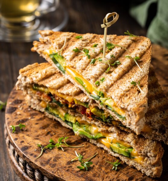 Healthy toasts with avocado, cheddar cheese and tomatoes for breakfast or lunch. Vegetarian sandwiches. Plant-based diet. Whole food concept.