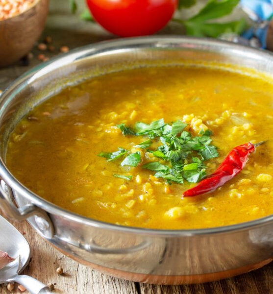 Indian food, real indian dish close-up. Traditional Indian spicy lentil puree soup with herbs on a rustic table.