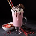 Strawberry milkshake with whipped cream and chocolate syrup with copyspace on dark background