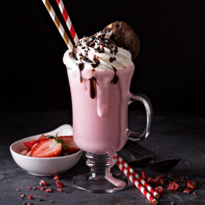Strawberry milkshake with whipped cream and chocolate syrup with copyspace on dark background
