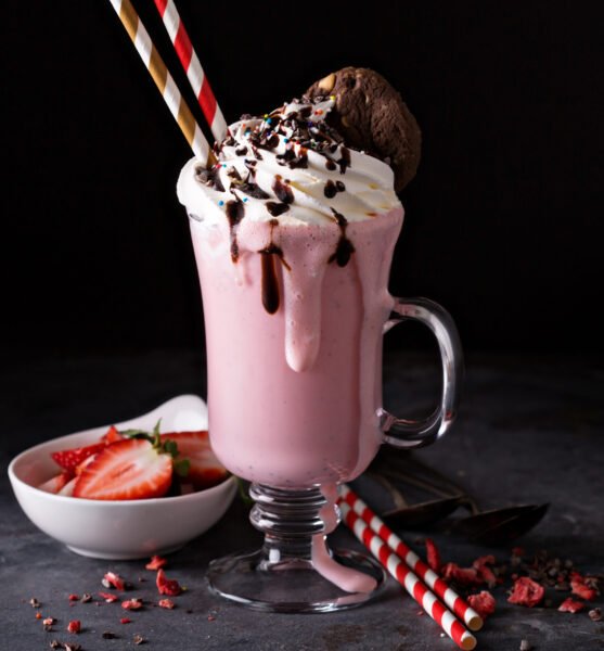 Strawberry milkshake with whipped cream and chocolate syrup with copyspace on dark background