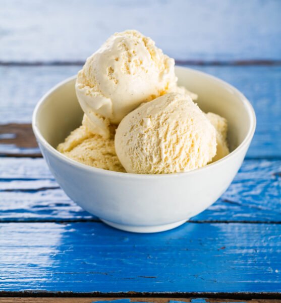 Tasty vanilla ice scoops in bowl on blue wooden rustic table. Closeup.