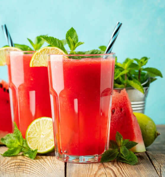 Watermelon slushie with lime and mint, summer refreshing drink in tall glasses on a light blue background. Sweet cold smoothie.